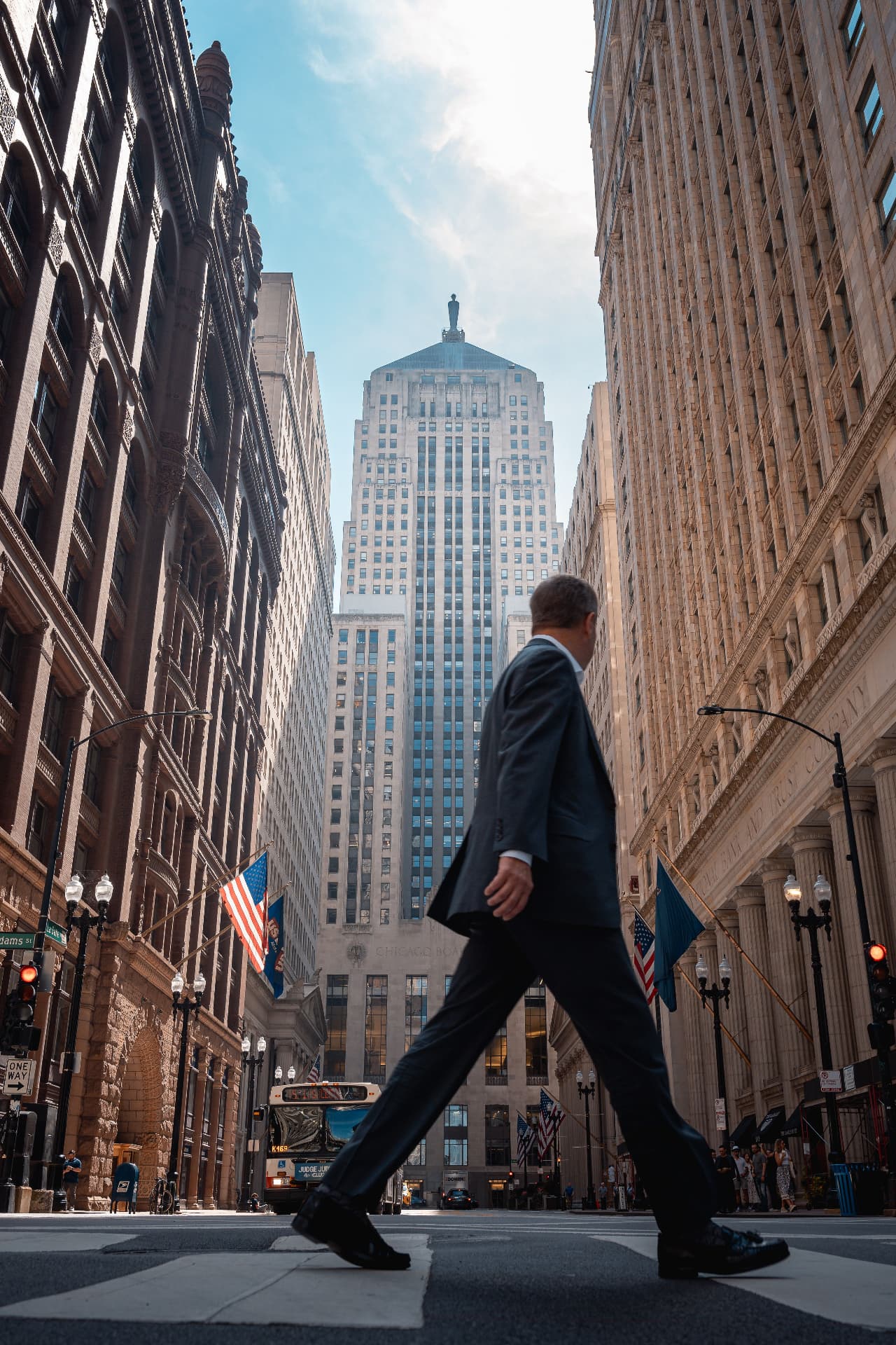 Executive in a suit walking across a city street with skyscrapers ahead, symbolizing career transition